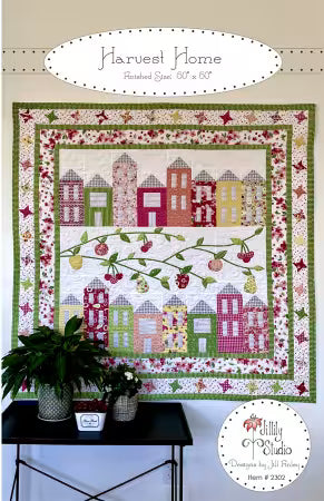 Front cover of the 'Harvest Home' quilt pattern by Jill Finley for Jillily Studio, showing a completed square quilt with a center layout of fabric-pieced houses and appliqued apple trees, surrounded by a pieced geometric star block border.