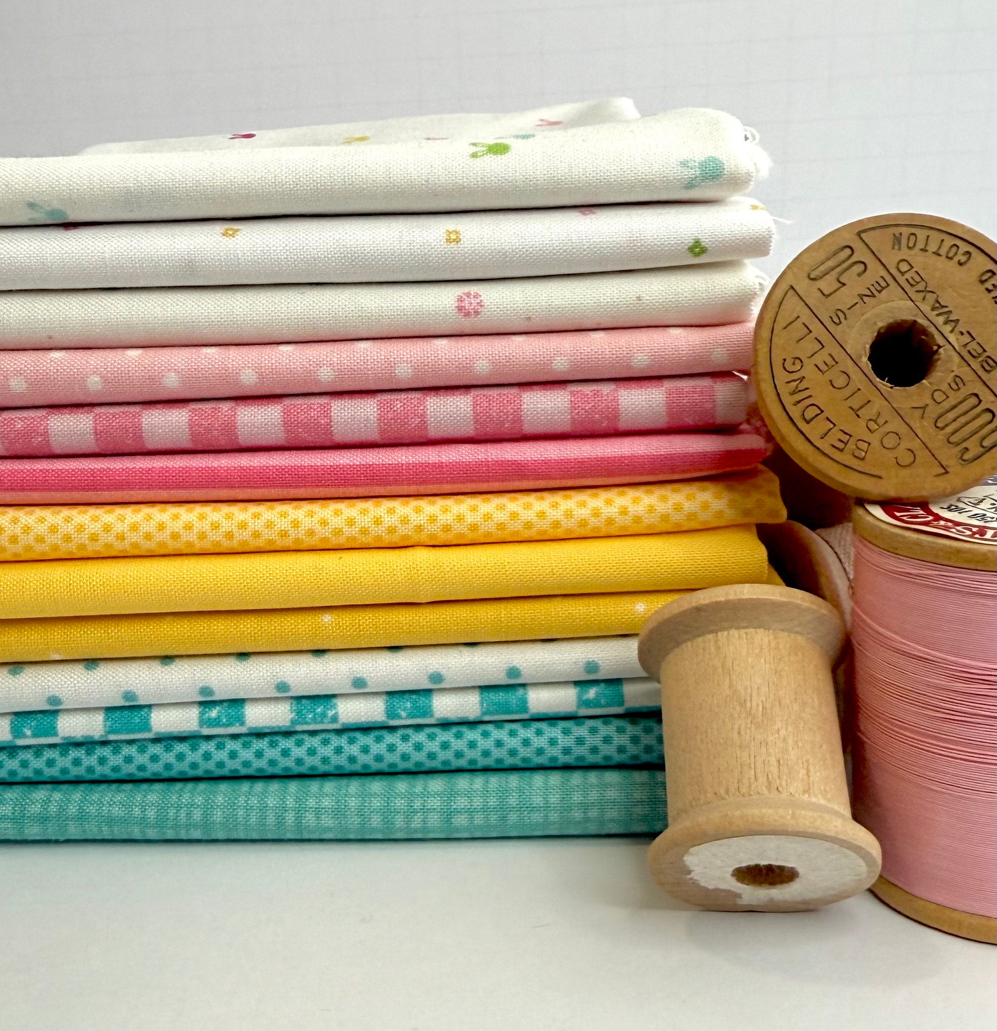 A stacked fabric bundle featuring Riley Blake Designs Basics in a palette of teal, yellow, pink, and white prints including checkers, stripes, and dots