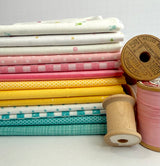 A stacked fabric bundle featuring Riley Blake Designs Basics in a palette of teal, yellow, pink, and white prints including checkers, stripes, and dots